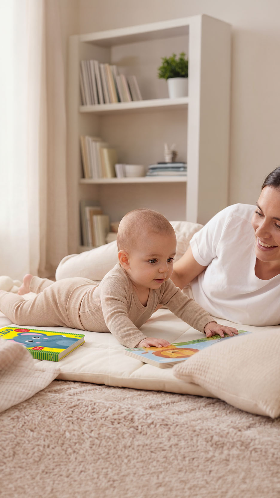 Baby and mother on a playmat, with children's books and a bookshelf in the background.