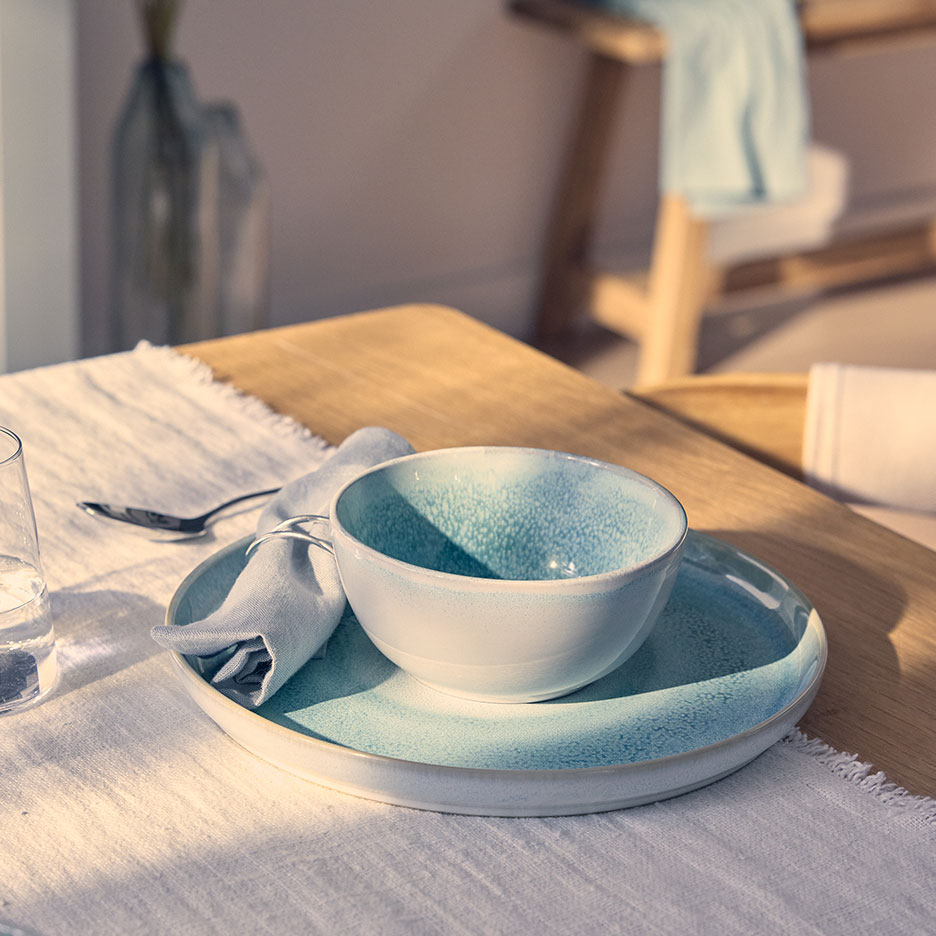 Table setting with a light blue bowl and plate on a white placemat.