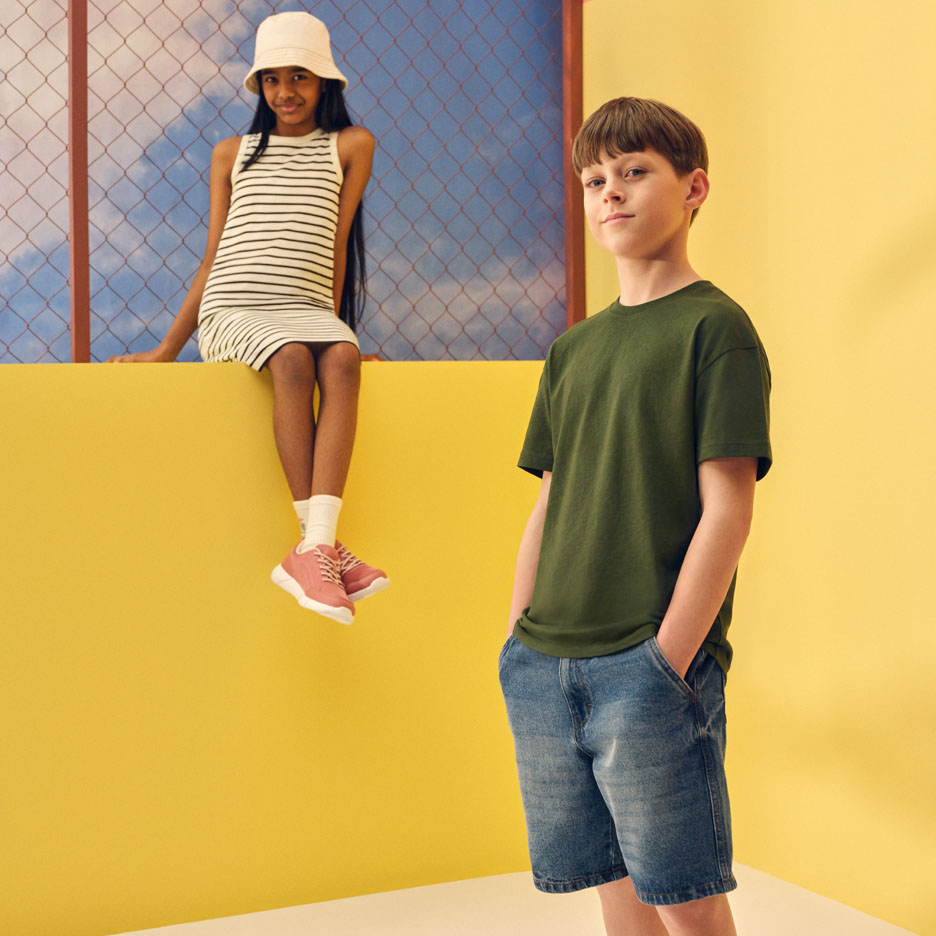 Kids' summer fashion: girl in striped dress and bucket hat, boy in green t-shirt and denim shorts.