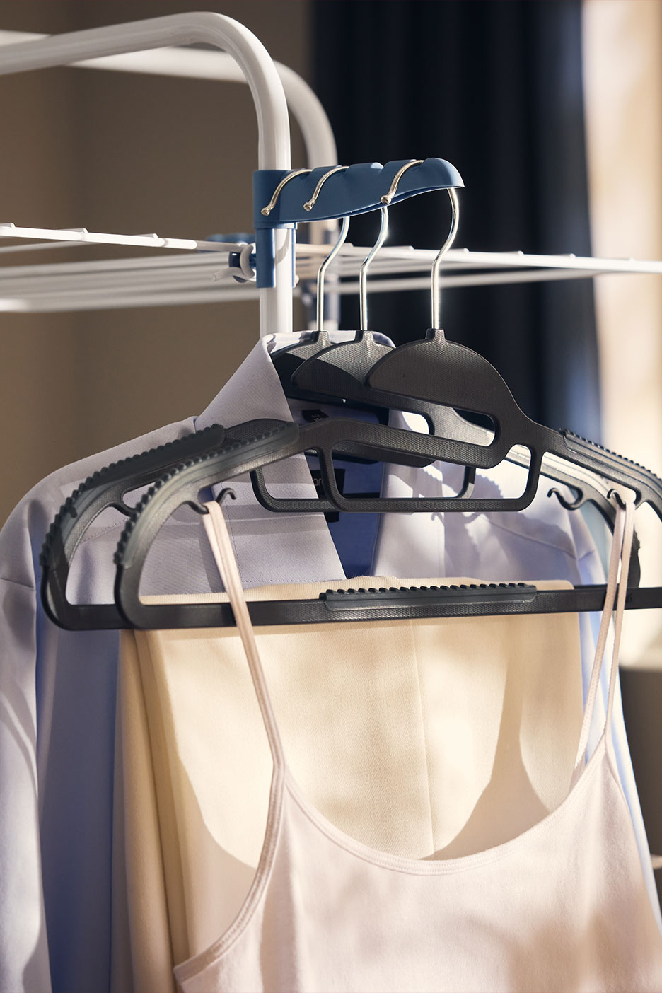 Clothes on hangers: shirt, trousers, and a top on a clothes drying rack.
