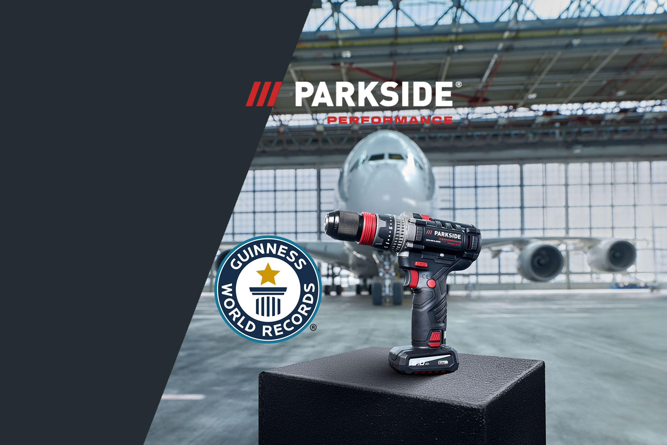 Drill with Guinness World Records logo in front of an airplane in a hangar.