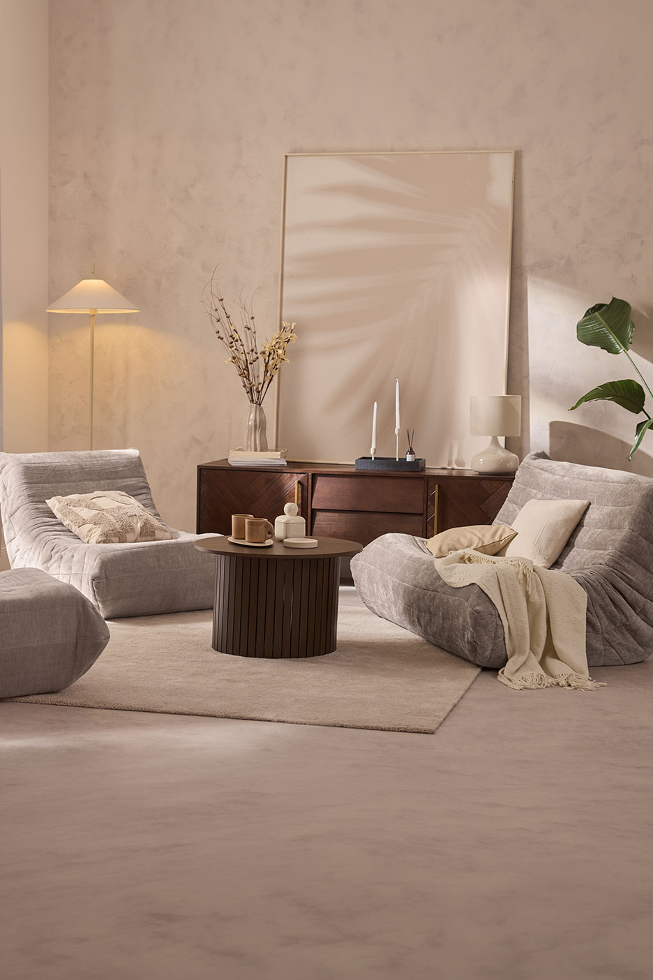 Living room with grey lounge chairs, wooden coffee table, and sideboard with decor.
