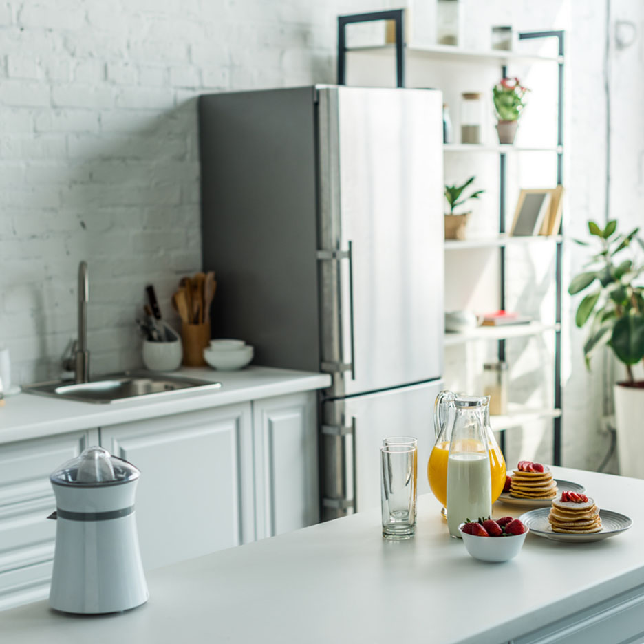 Orange juice, milk, and pancakes in a modern kitchen.